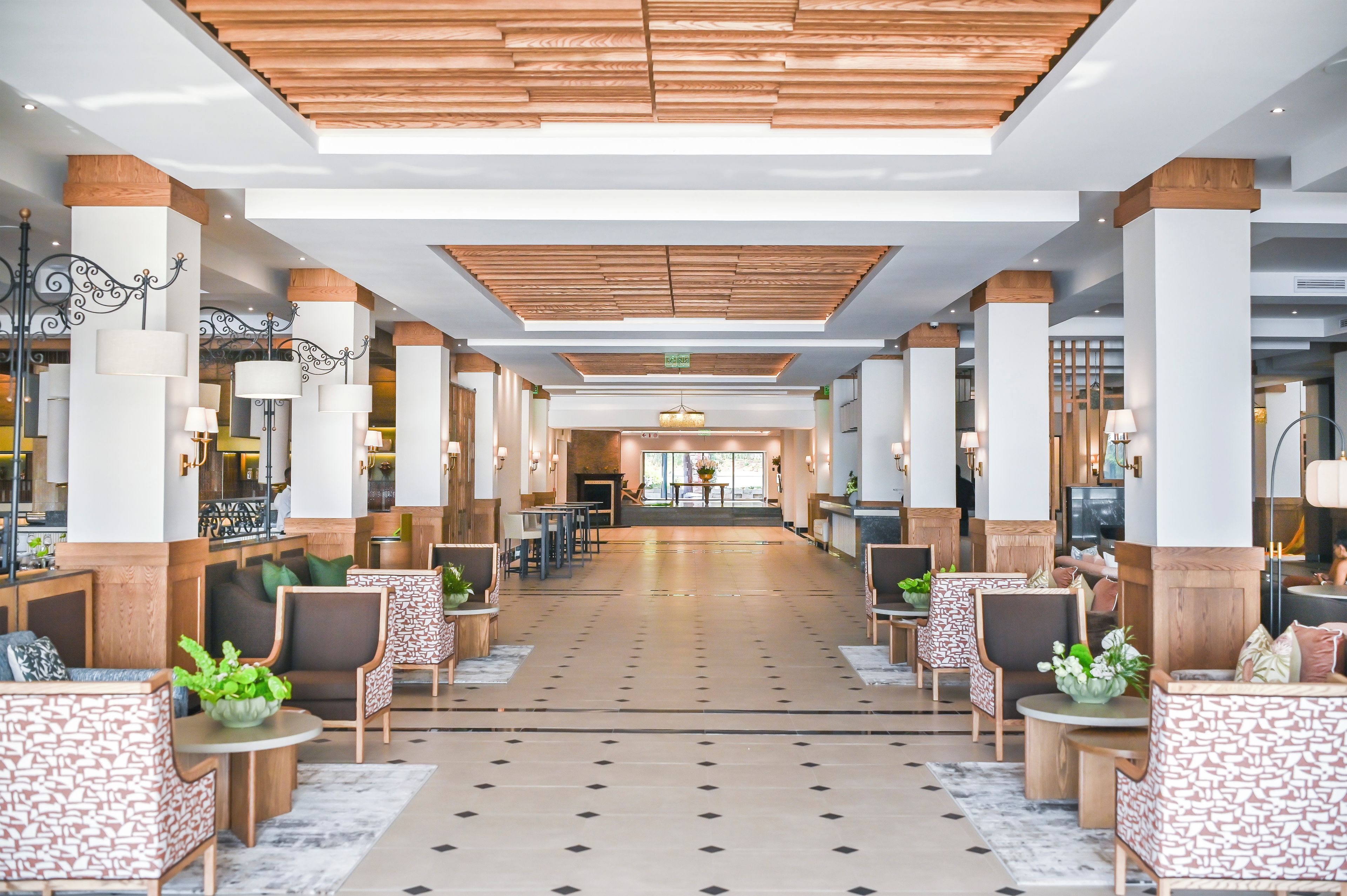 A spacious lobby with a central open area, seating arrangements, and a modern ceiling design.