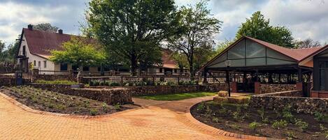 A brick pathway leading to a building with a glass roof and a stone wall.