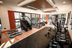 A gym with cardio machines, free weights, and a brick wall. - Irene Country Hotel (Irene, Centurion)