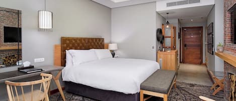 Une chambre d’hôtel équipée d’un lit, d’un bureau, d’une chaise, d’une télévision, d’un ventilateur de plafond et d’une cheminée.