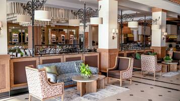 Un vestíbulo de hotel con zona de estar, mostrador de recepción y bar.