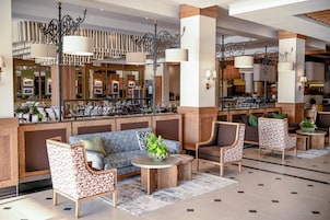 Un vestíbulo de hotel con zona de estar, mostrador de recepción y bar.