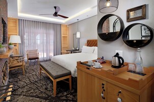 A hotel room with a bed, bedside table, chair, desk, and a large mirror.