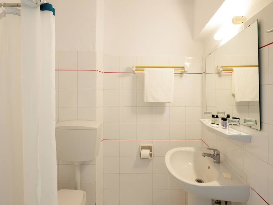 A bathroom with a toilet, sink, and mirror.