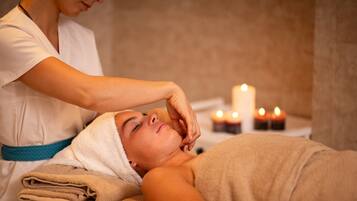 En person modtager massage i et rum med stearinlys og et håndklæde.