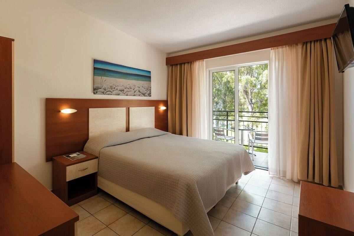 A hotel room with a bed, nightstand, and a painting on the wall.