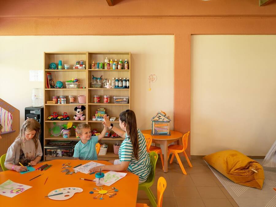 Una sala de juegos infantil con un teatro de marionetas, una casita y un tipi.