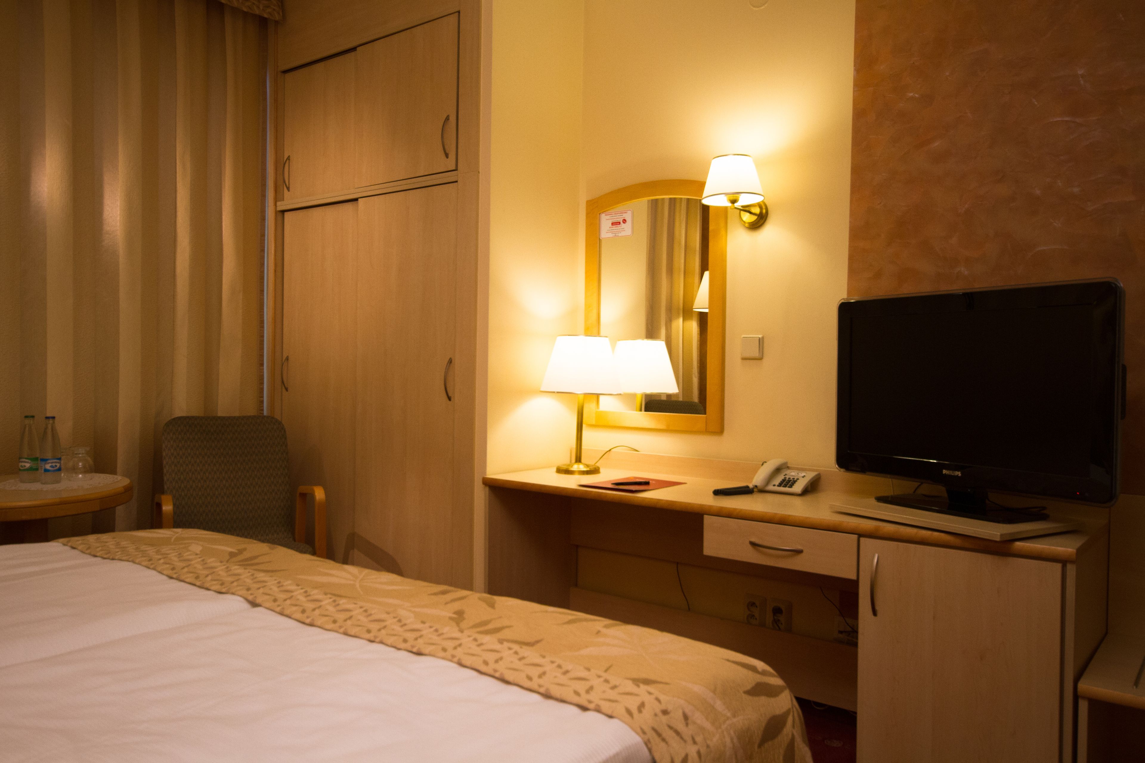 Une chambre d’hôtel avec un lit, un bureau avec une lampe, une télévision et une chaise.