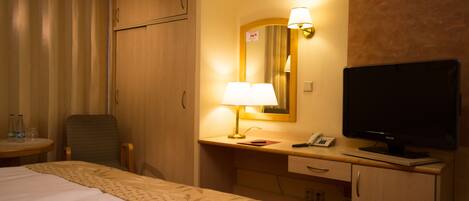 Une chambre d’hôtel avec un lit, un bureau avec une lampe, une télévision et une chaise.