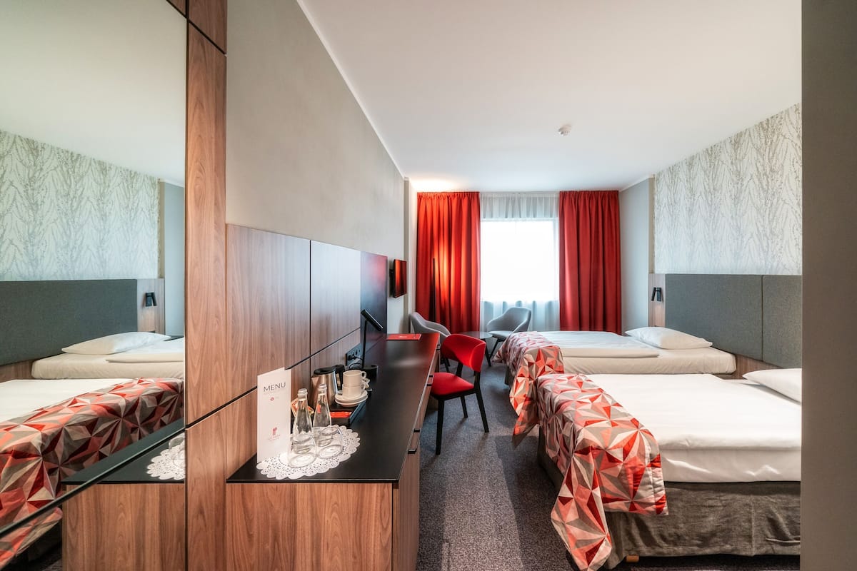 Une chambre d’hôtel avec deux lits, un bureau avec un menu, et une télévision.