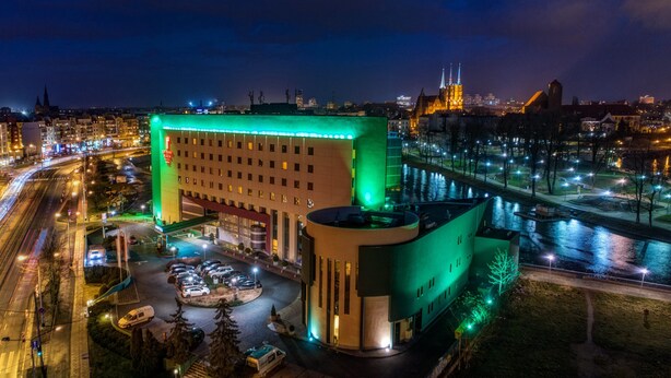 Un hôtel doté d’une cour intérieure, entourée d’un parking et bordé par une rivière.