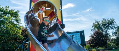 A child sliding down a metal slide at a playground.