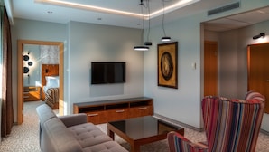 Un salon moderne avec un canapé, un fauteuil à rayures, un téléviseur à écran plat et un meuble de rangement en bois.