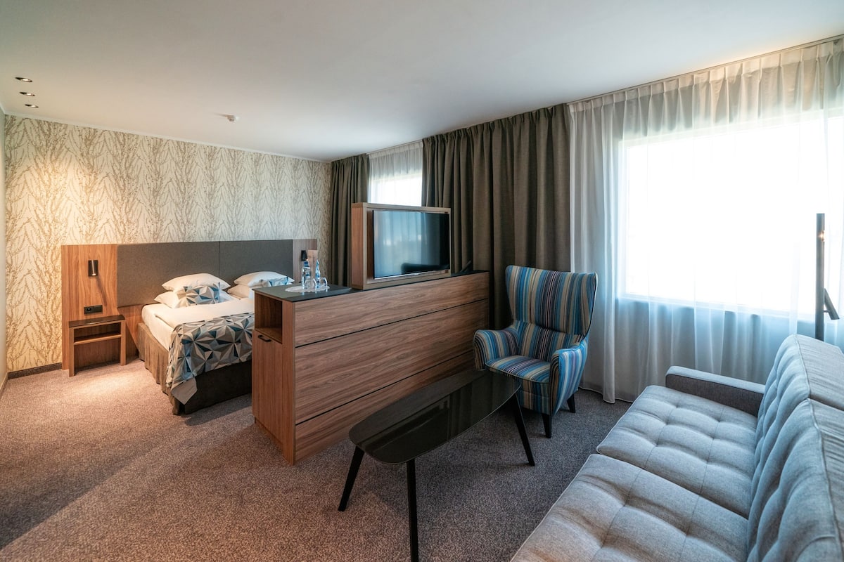 Une chambre d’hôtel équipée d’un lit, d’une télévision, d’un canapé, d’une chaise et d’un bureau.