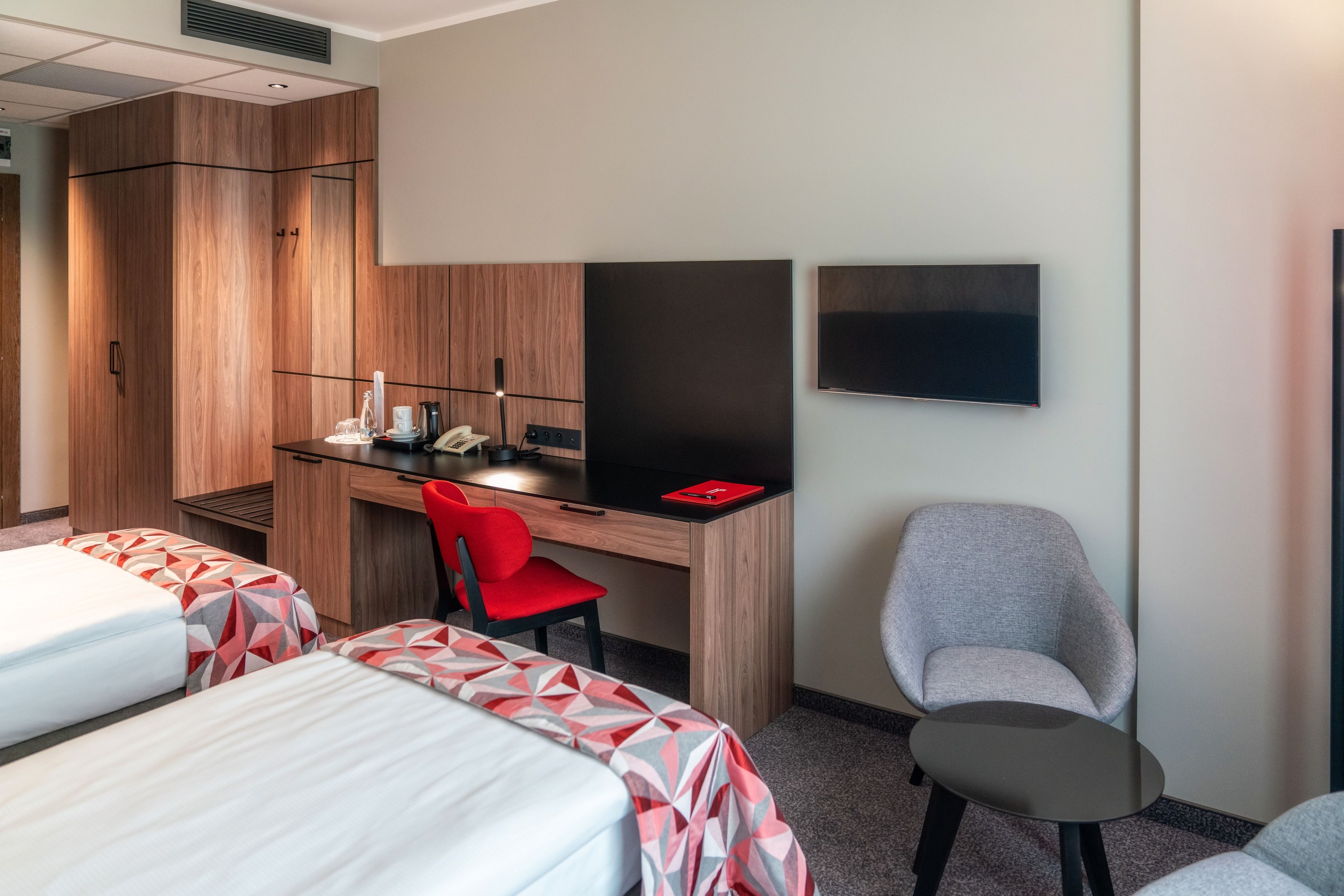 Une chambre d’hôtel avec deux lits, un bureau avec une chaise, un téléviseur à écran plat et une petite table.