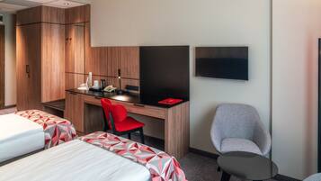 Une chambre d’hôtel avec deux lits, un bureau avec une chaise, un téléviseur à écran plat et une petite table.