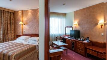A hotel room with a bed, desk, chair, and a television.