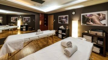 Relax in a serene space with two massage therapy beds, a clock, and amenities at the ready.