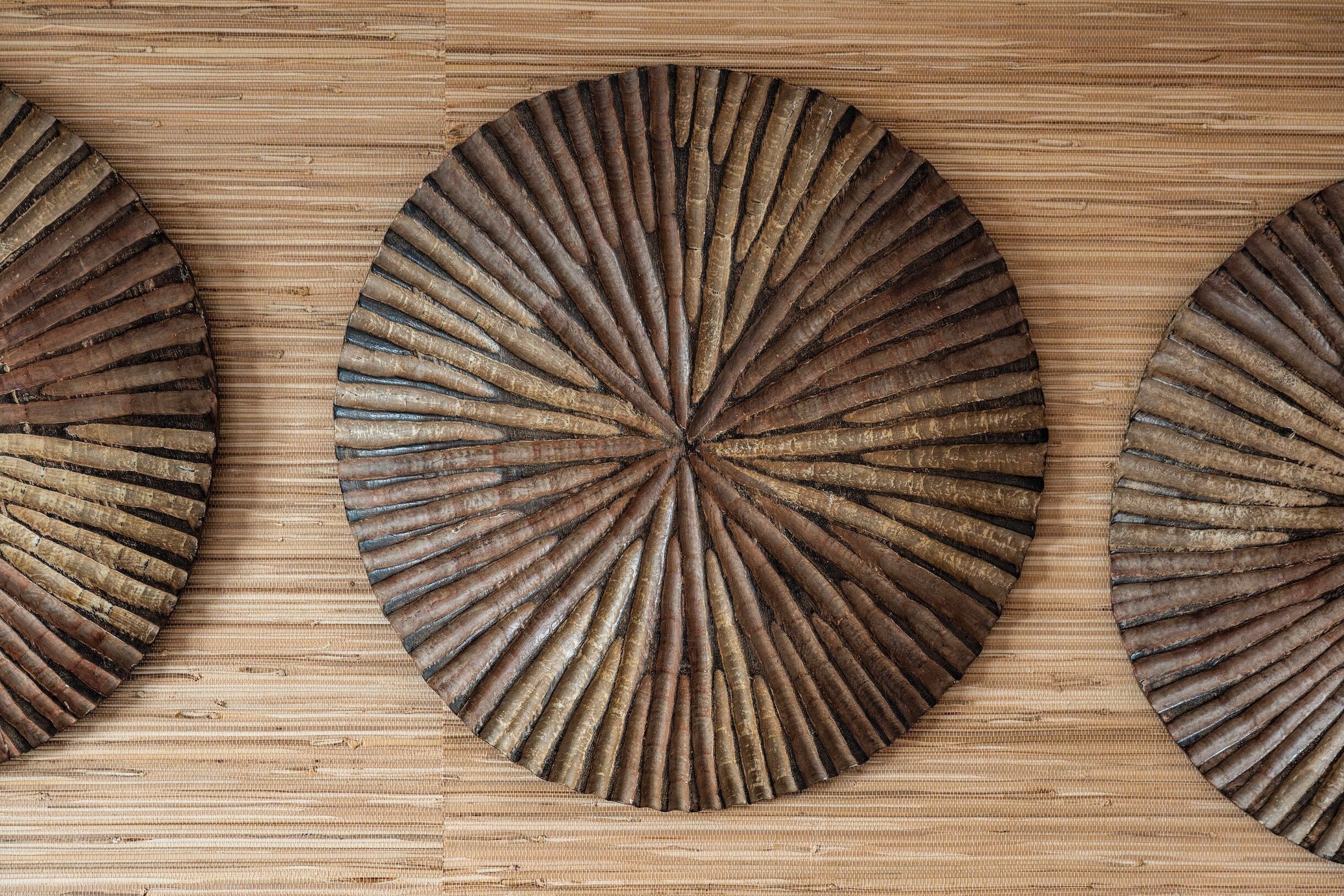 Tres paneles de madera redondos con un diseño radial, sobre una superficie de madera.