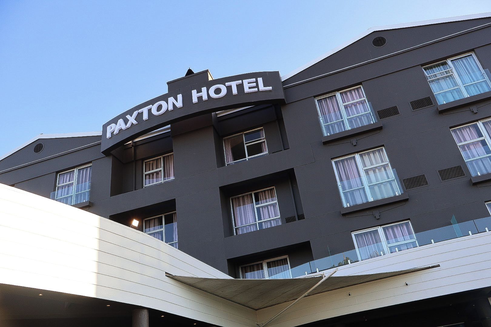 A multi-story building with a sign that reads 'Paxton Hotel.'