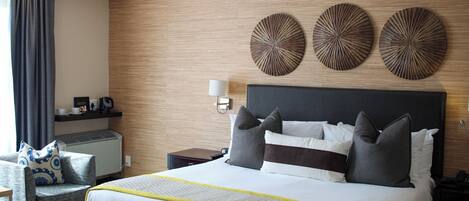 Habitación de hotel con una cama grande, una mesita de noche, una silla y decoración en la pared.