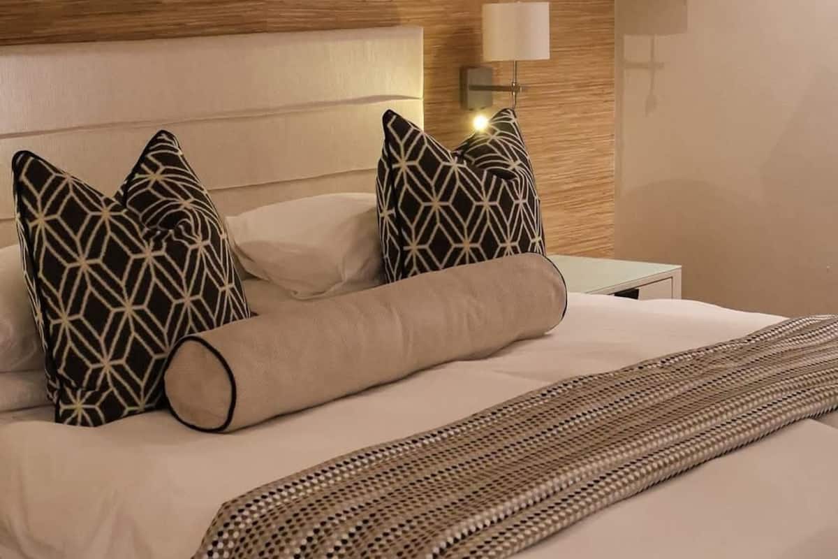 A neatly made bed with patterned pillows and a decorative throw.