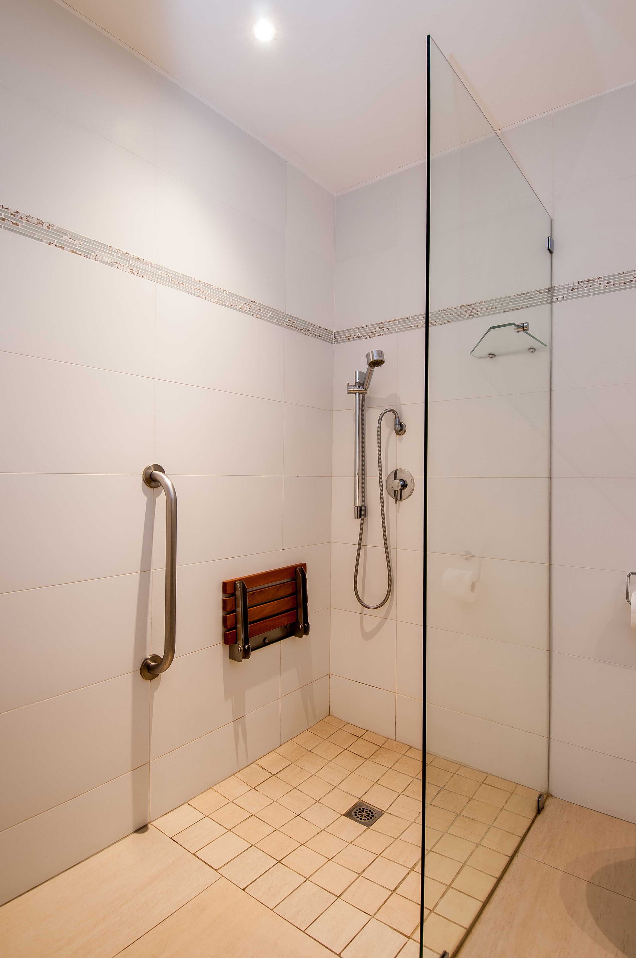 A modern bathroom with a glass shower enclosure, a handheld showerhead, a handheld showerhead, and a towel rack.