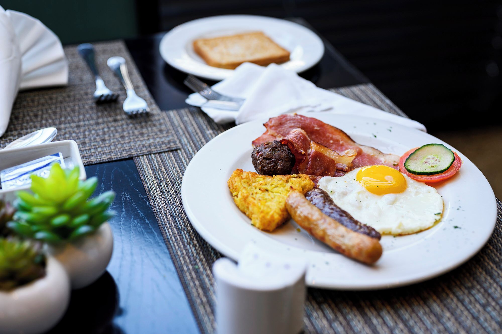 Un plato de desayuno con huevos, tocino, salchichas y tostadas.