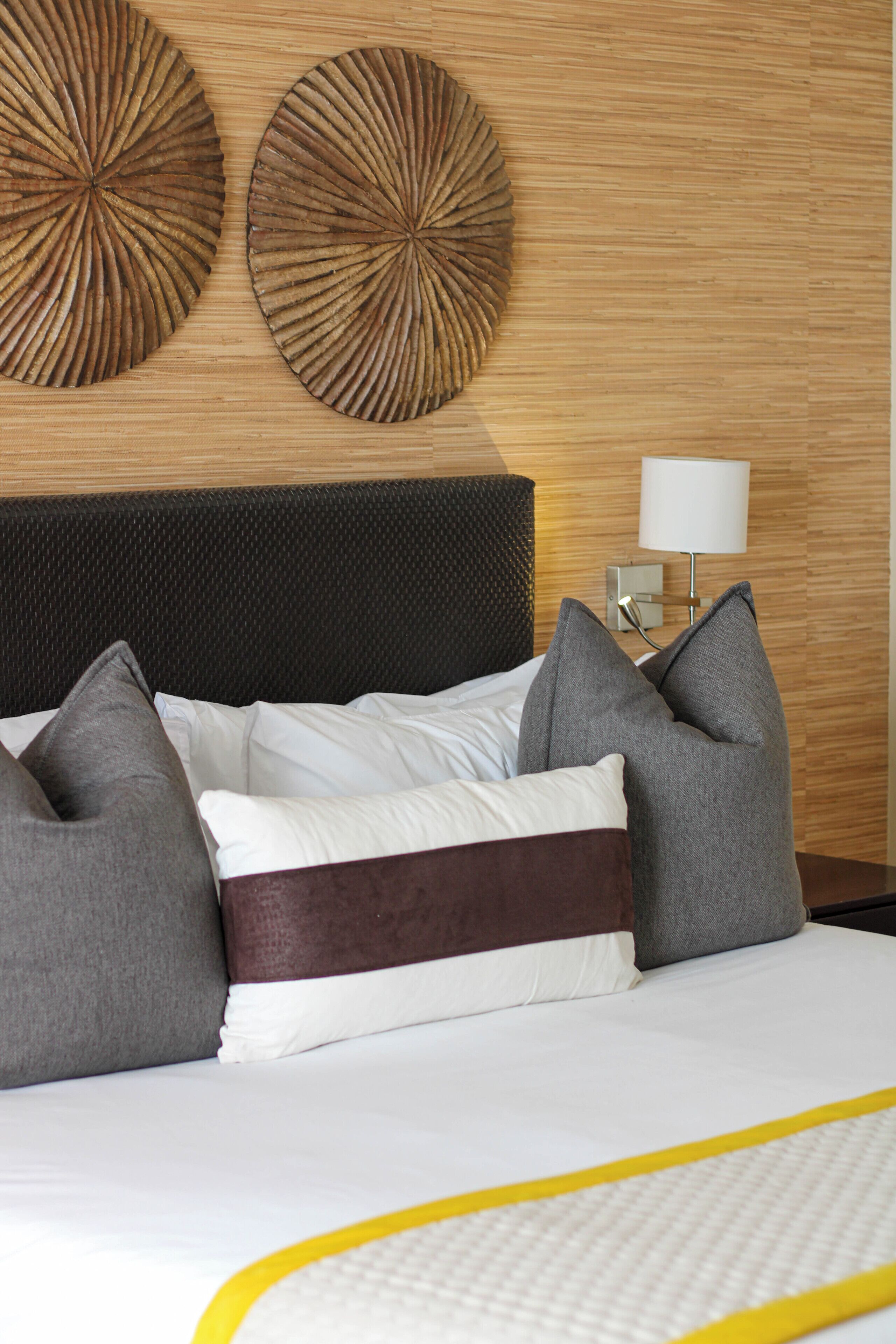 A neatly made bed with a brown headboard, white and gray pillows, and a yellow accent strip.