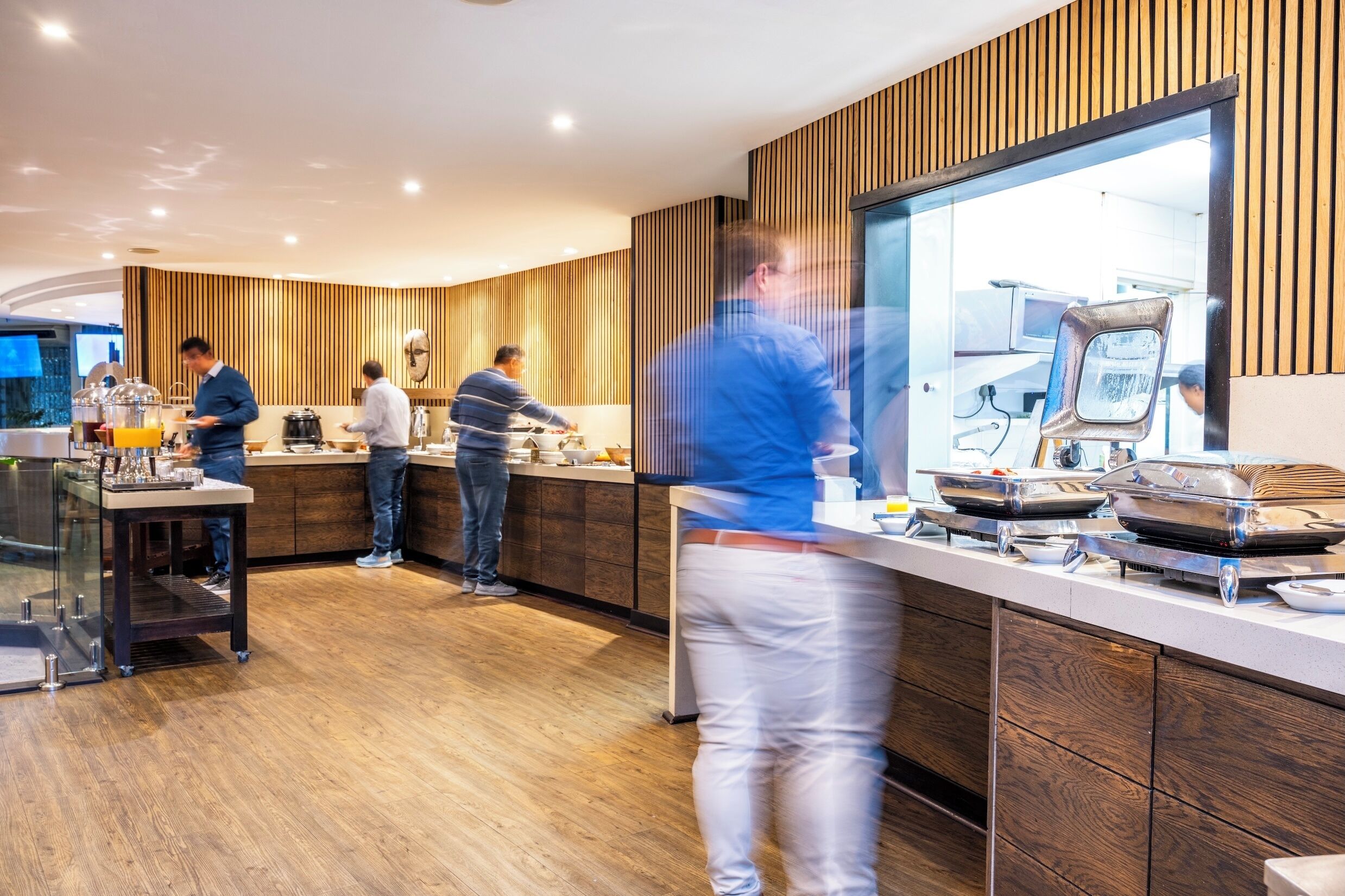 A modern kitchen area with wooden paneling, a glass partition, and stainless steel appliances.