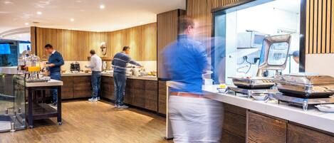 A modern kitchen area with wooden paneling, a glass partition, and stainless steel appliances.
