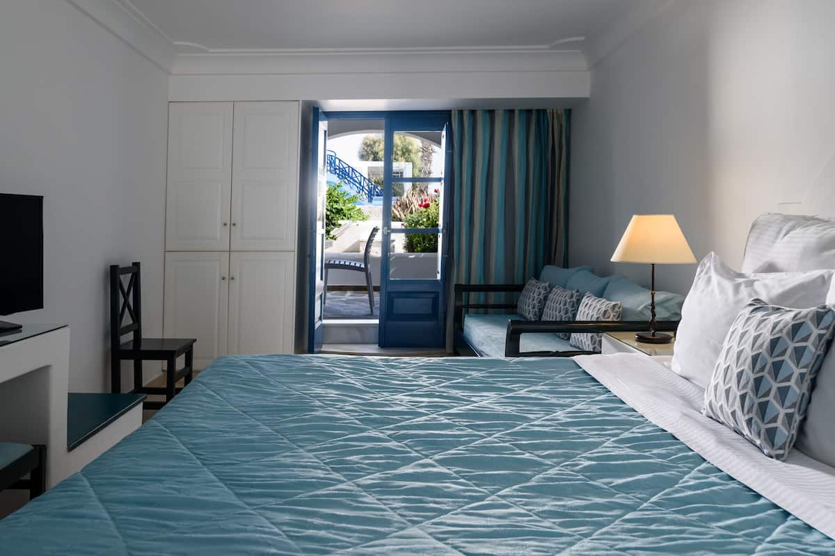 A hotel room with a bed, a TV, a desk, and a chair.