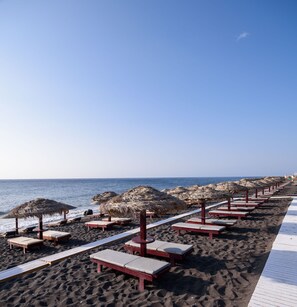 On the beach, black sand, sun-loungers, beach umbrellas