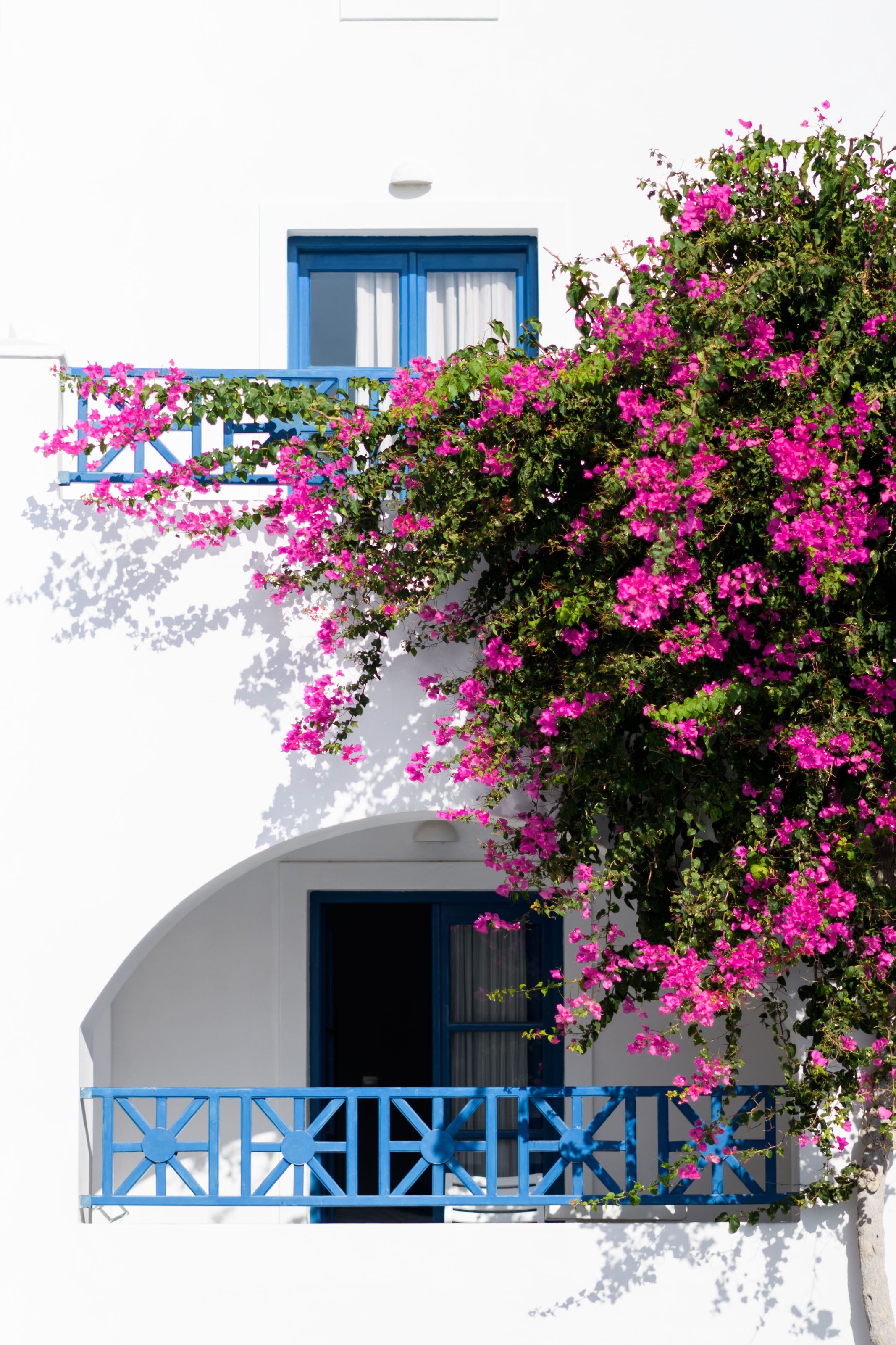 A white building with a blue balcony and a window.