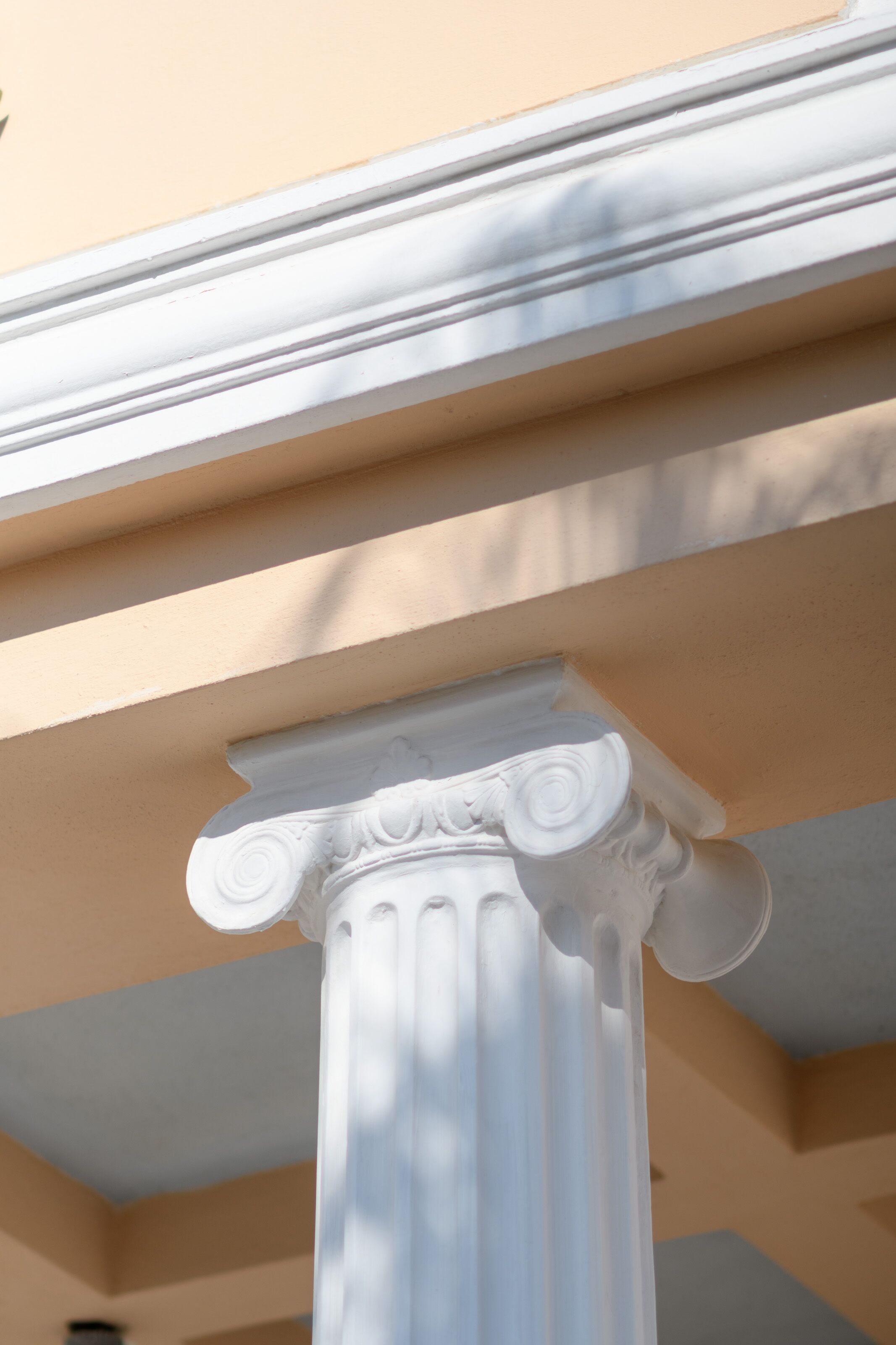 A white architectural column with intricate carvings, part of a building's exterior.