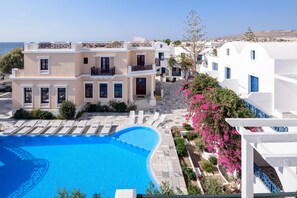 A multi-story building with a swimming pool, white and beige exterior, and balconies. - Veggera Hotel (Santorini)
