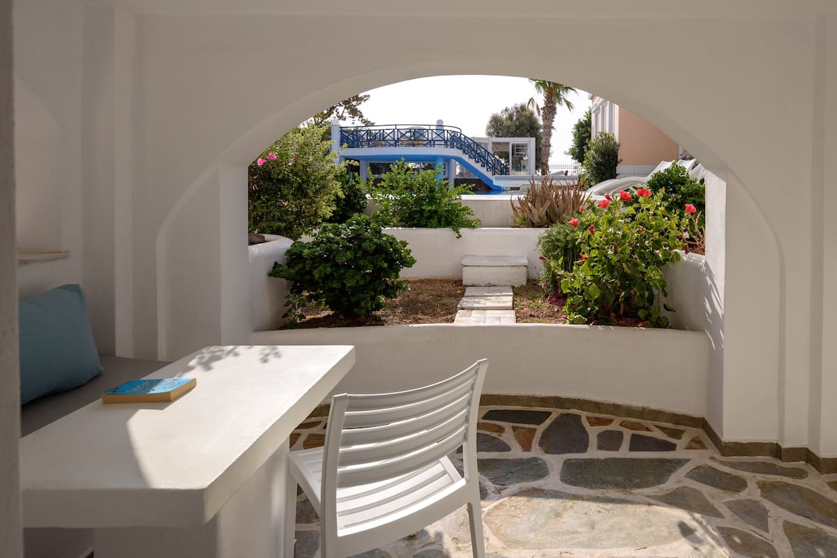 A white interior space with a stone floor, a white table with a book, and a white chair.