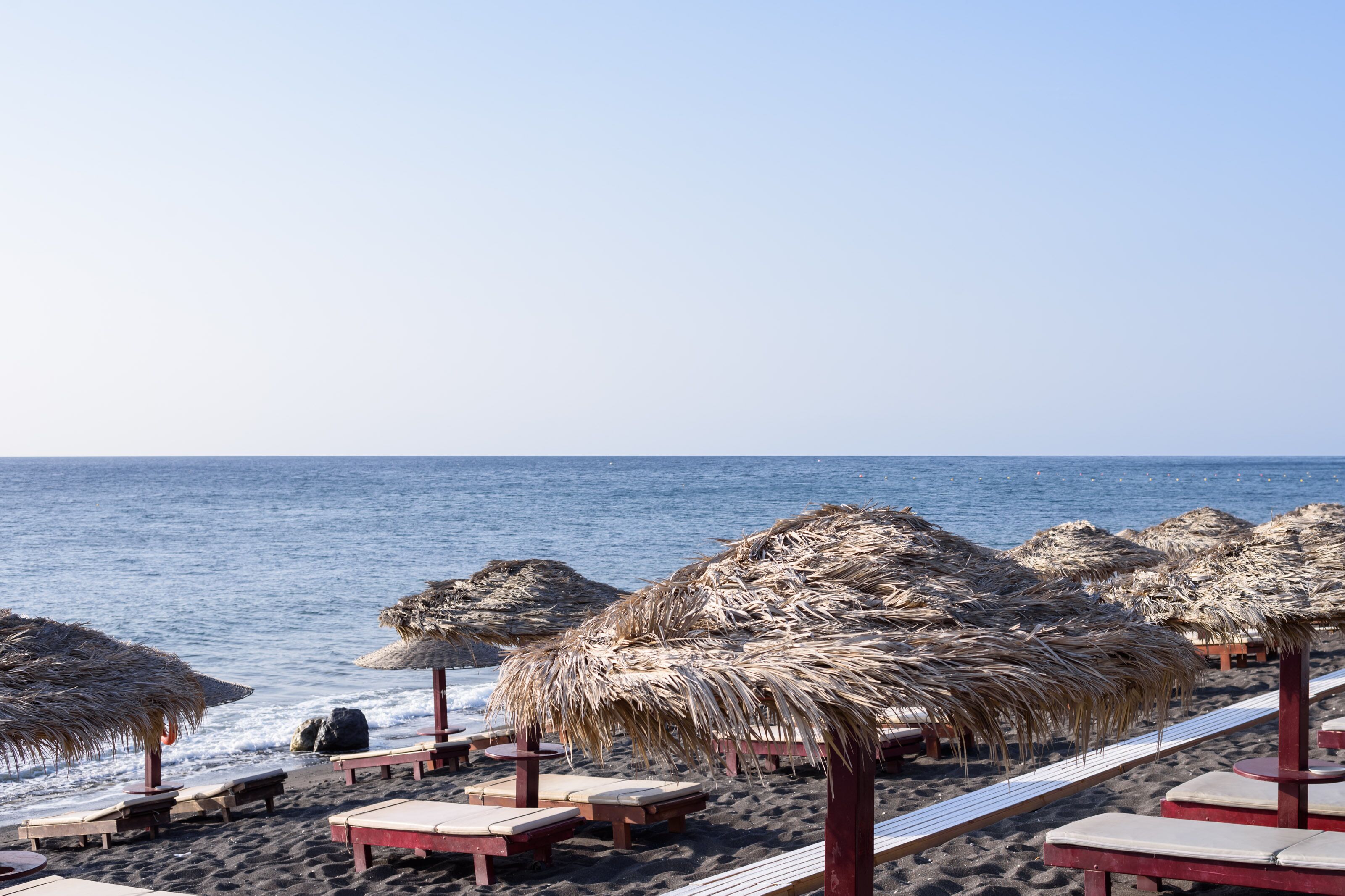 On the beach, black sand, sun-loungers, beach umbrellas