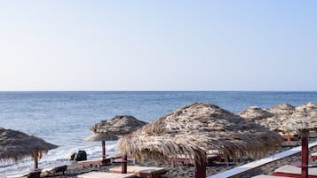 On the beach, black sand, sun-loungers, beach umbrellas