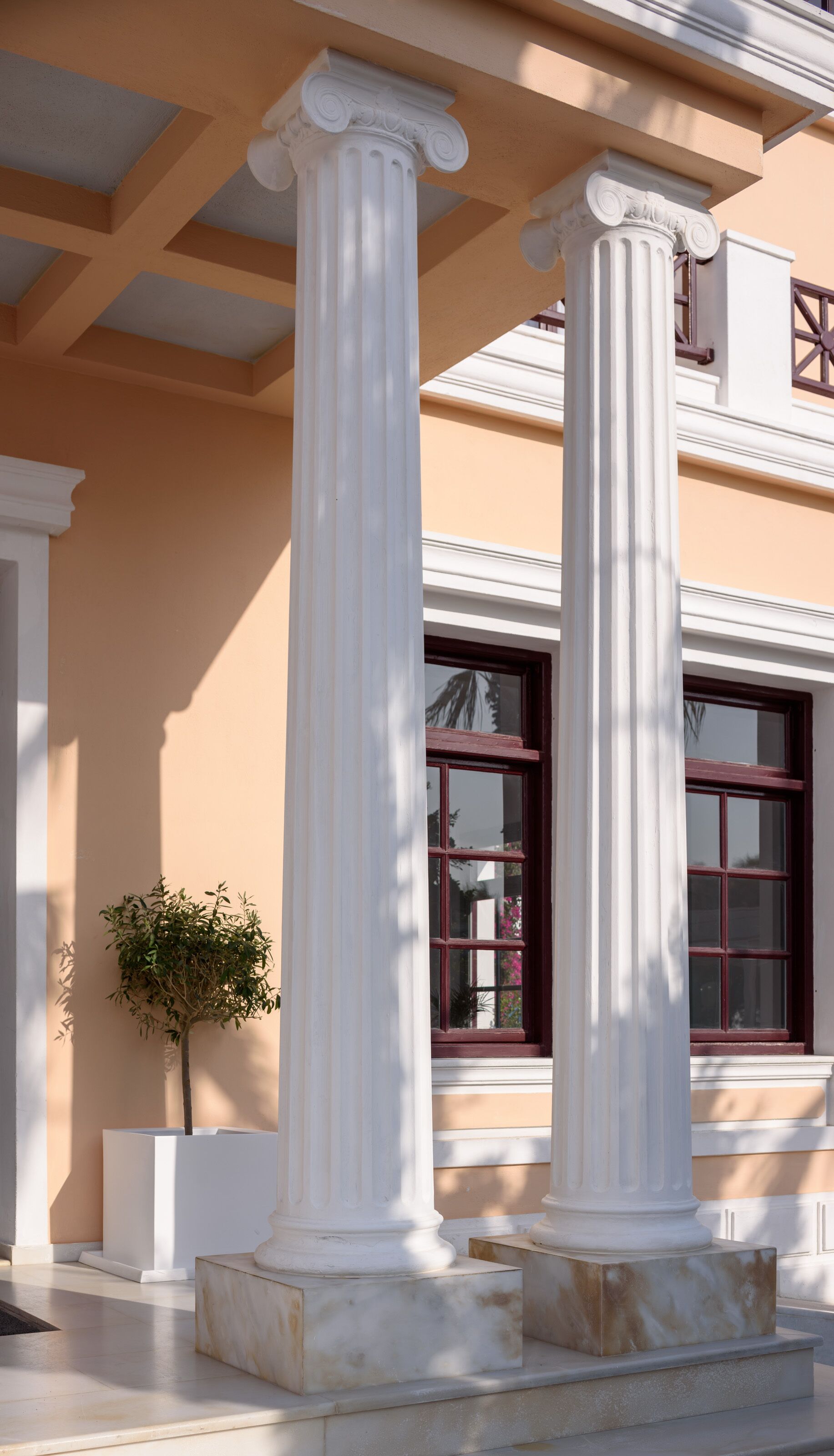 A building facade with classical columns and a window with a red frame.
