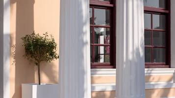 A building facade with classical columns and a window with a red frame.
