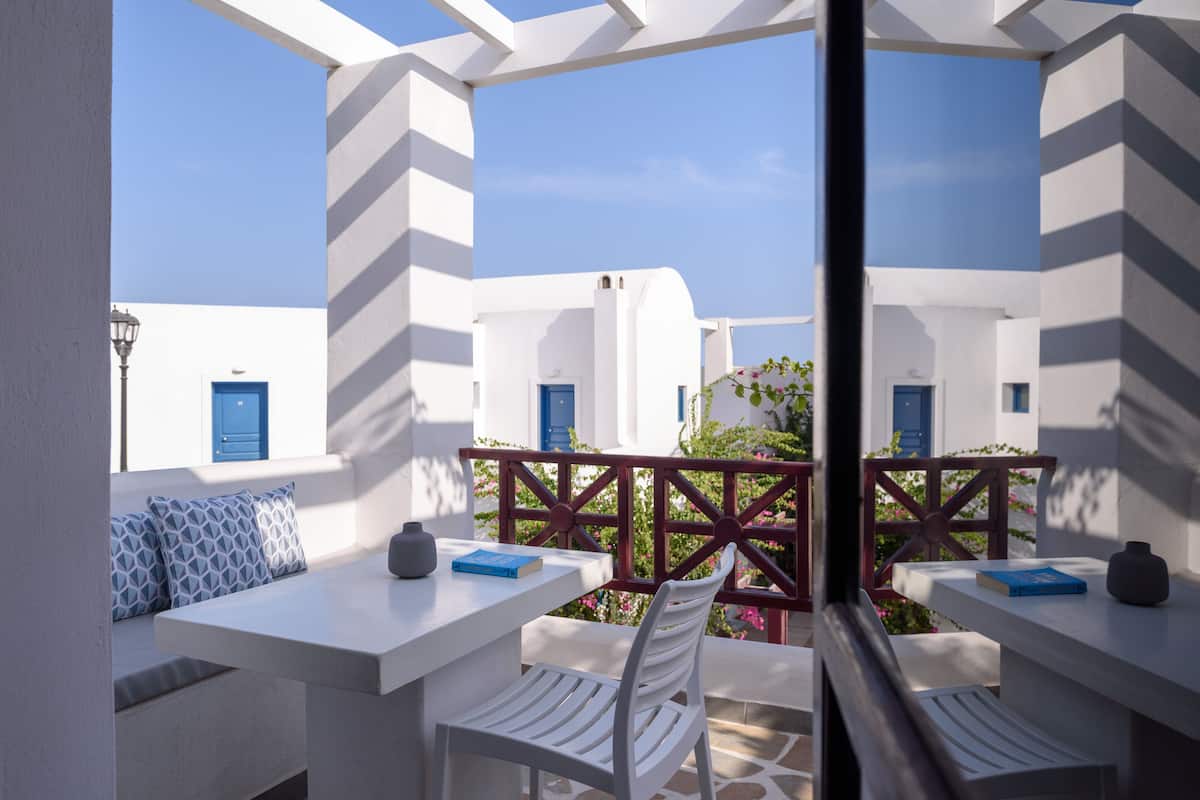 A terrace with white furniture and blue doors, offering a view of the surrounding buildings.