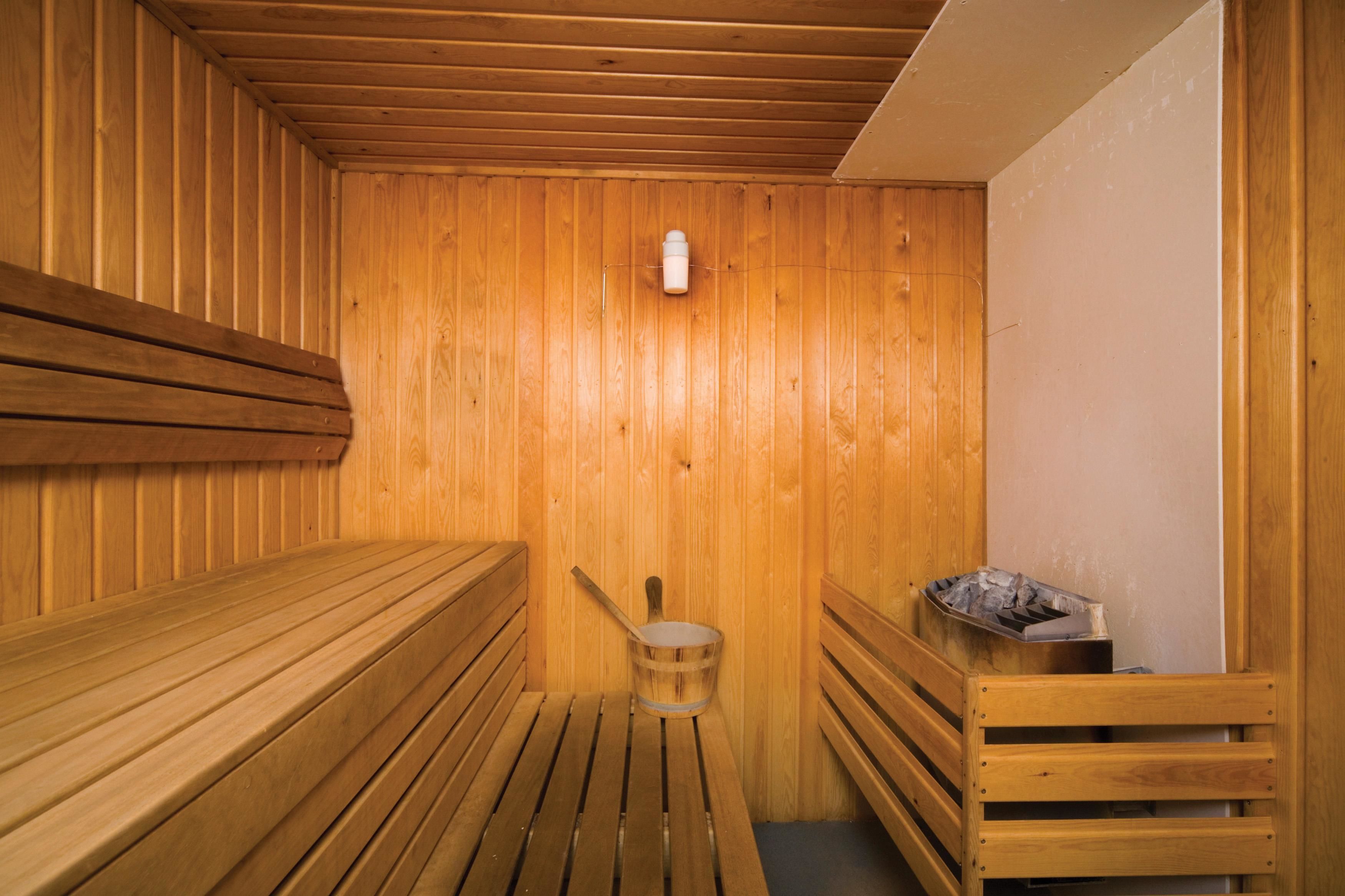 A wooden sauna with benches and a bucket.