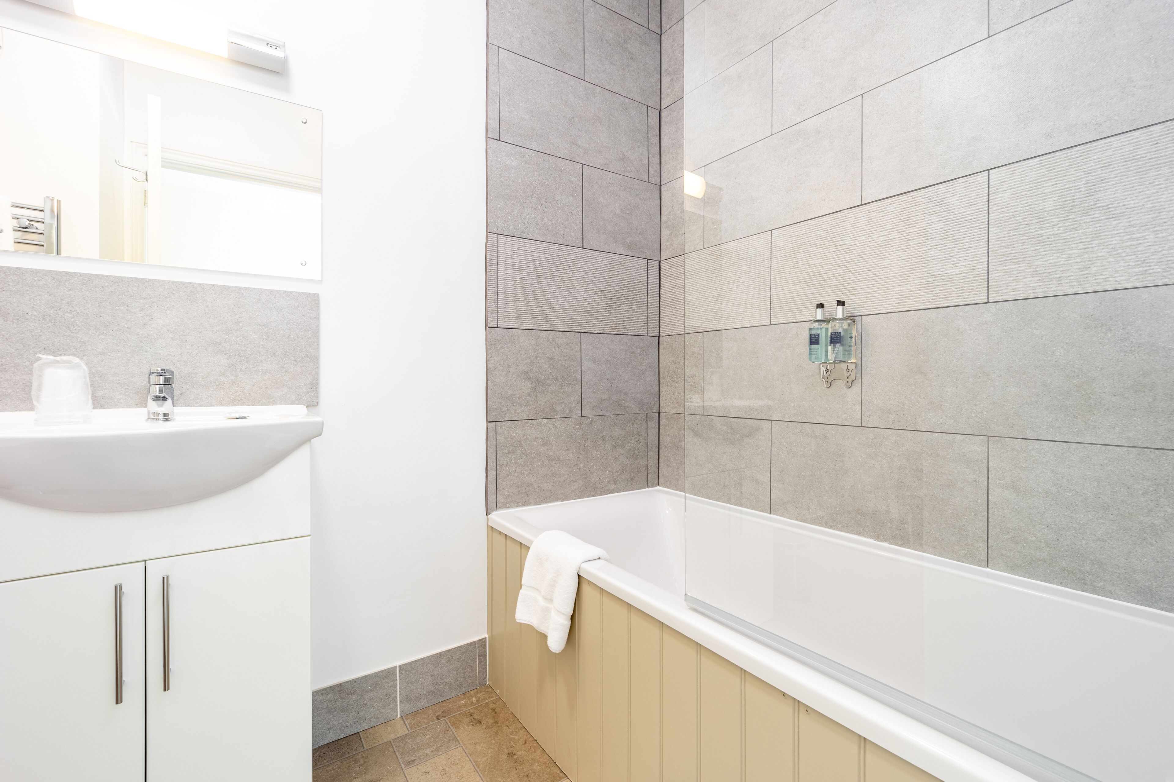 Une salle de bain moderne avec un lavabo blanc, une baignoire et un grand miroir.