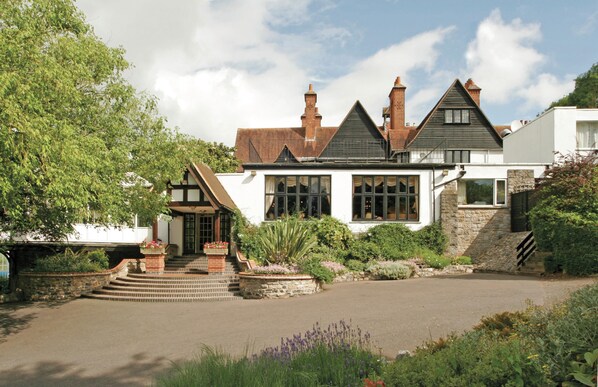 A traditional house with a stone staircase, a front garden, and a driveway.