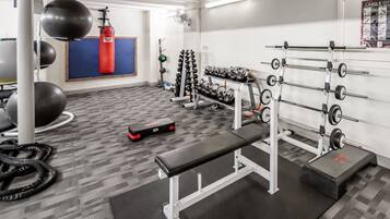 Un gimnasio con bancos, jaulas para pesas y pelotas de ejercicio.