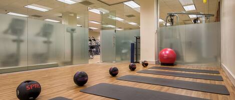 A gym with exercise mats, a red exercise ball, and a treadmill.