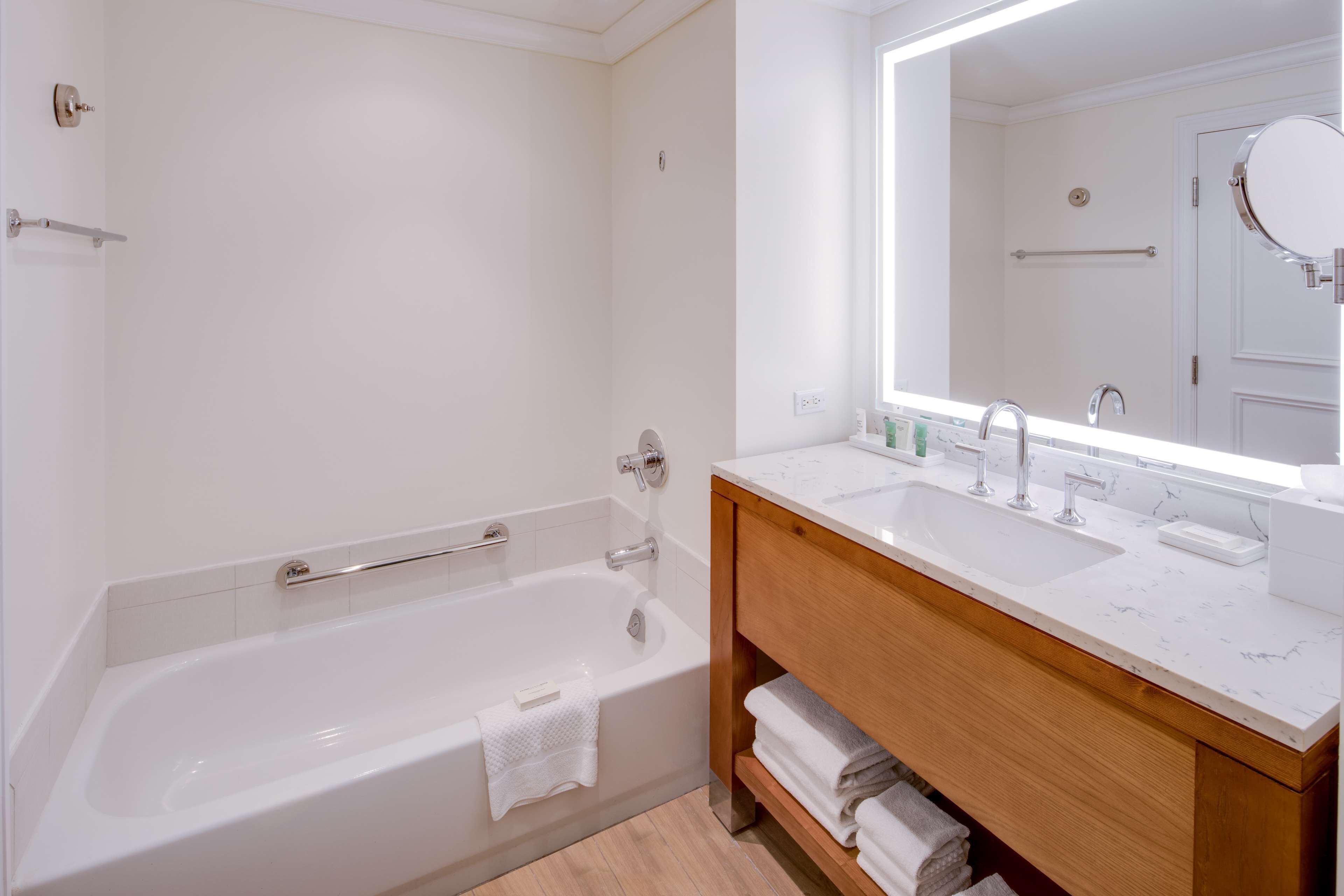 Une salle de bain moderne avec une baignoire blanche, un meuble-lavabo doté de deux vasques et un grand miroir.