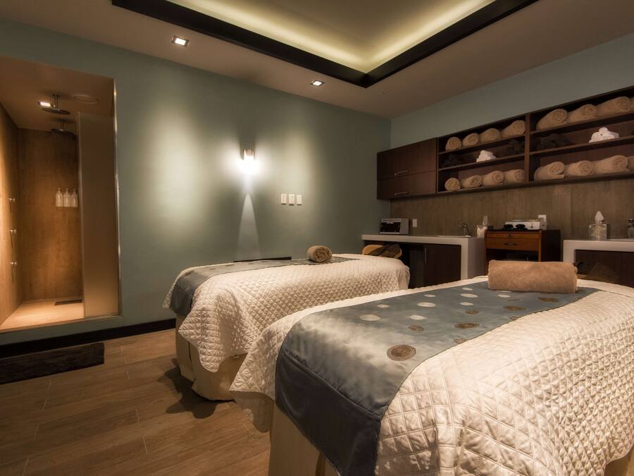 Una habitación de hotel moderna con dos camas, ducha integrada y un estante con toallas.