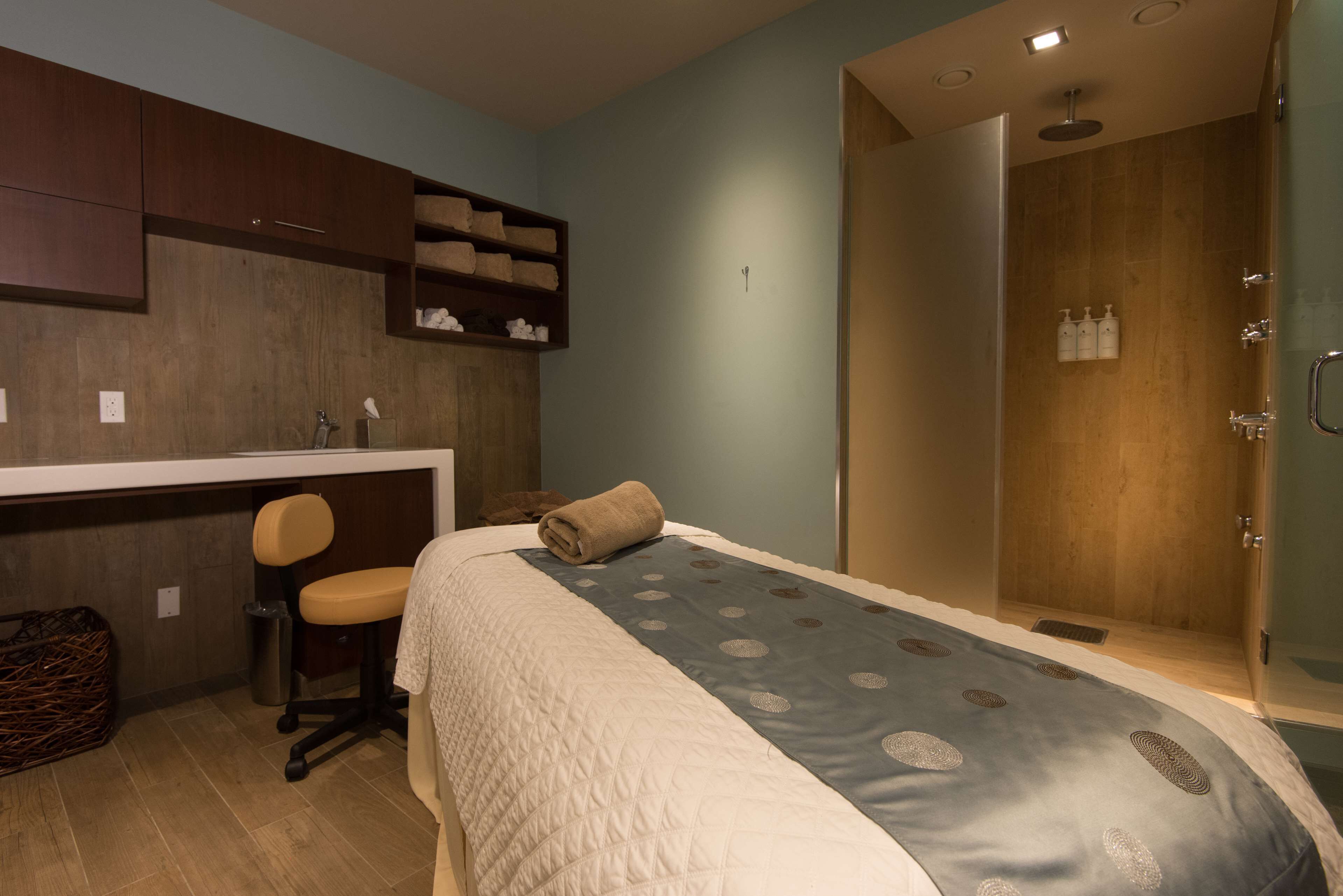 Une chambre comprenant un lit, un bureau, une chaise, un espace douche et une petite étagère avec des serviettes.